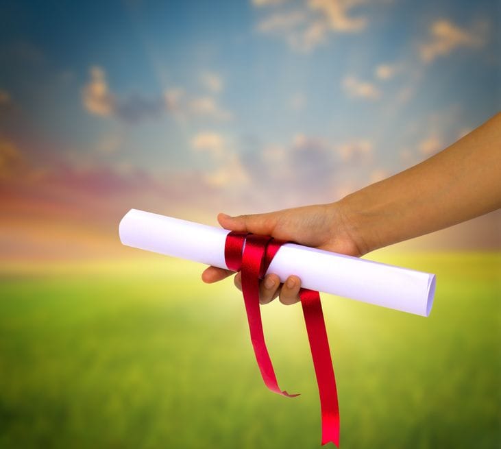 Hand holding Diploma wrapped with a red ribbon.