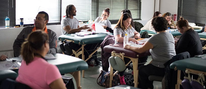 IntelliTec College Massage Therapy students are studying in a room with many massage tables